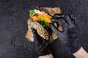 mains-femme-dans-gants-caoutchouc-noirs-tiennent-burger-pain-noir-juteux_107389-22.webp